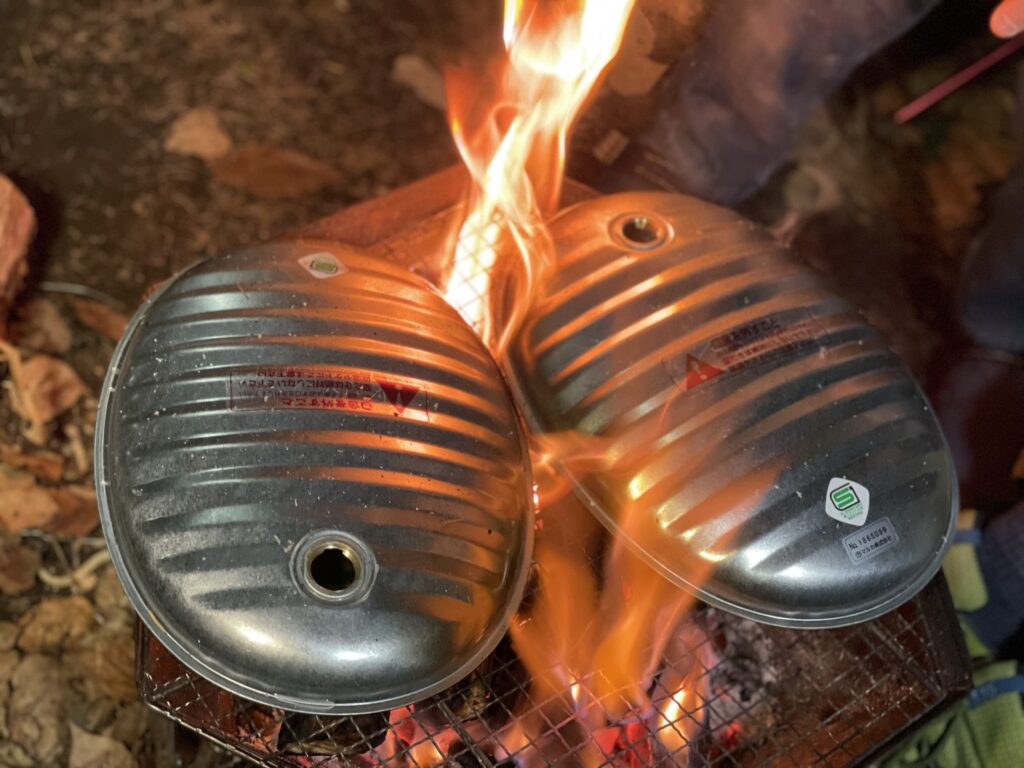 焚火で湯たんぽを温めている。煤がついて大変なので、ガスコンロで温めることをお勧めします