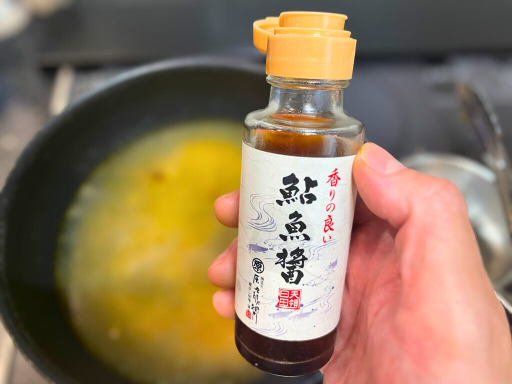 まるはら社の国産鮎魚醤を手に持っている様子