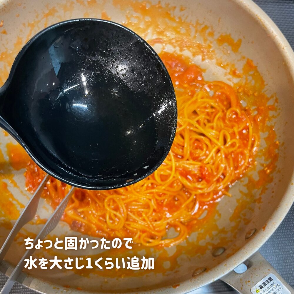 ワンパンで煮込んだアラビアータ。ソースが煮詰まりすぎてパスタが少し固めだったため、黒いお玉でお湯を大さじ1ほど追加して水分を調整している様子